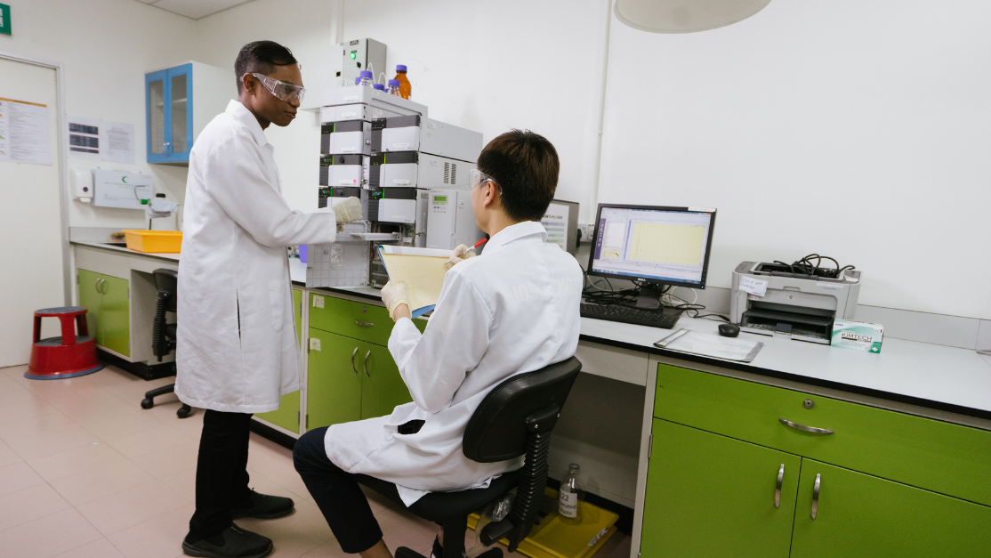 one standing and one seated student working in an analysis lab