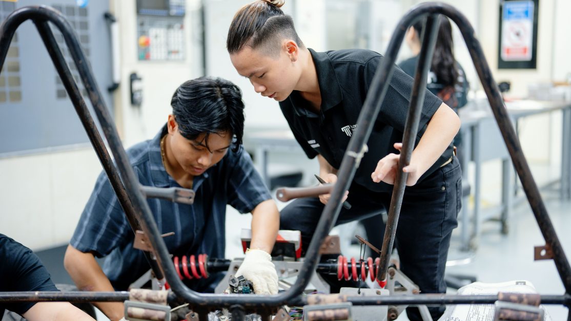 students working on the frame of a car