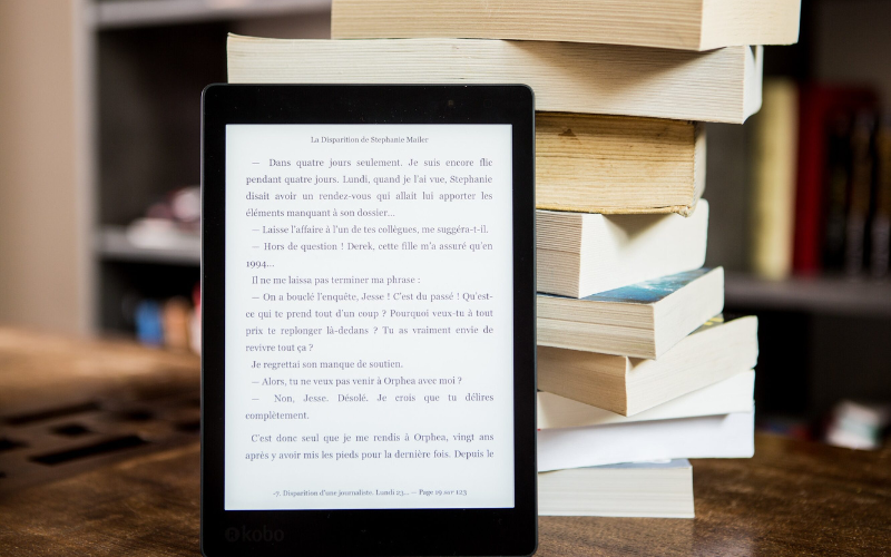 E-book reader lies in front of several books