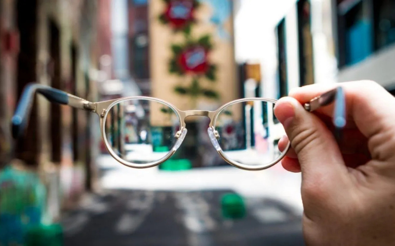A hand holding a pair of glasses