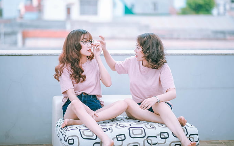 a girl adjusting another girl's glasses on a roof