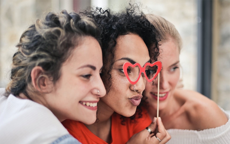 3 girls are taking picture together with props