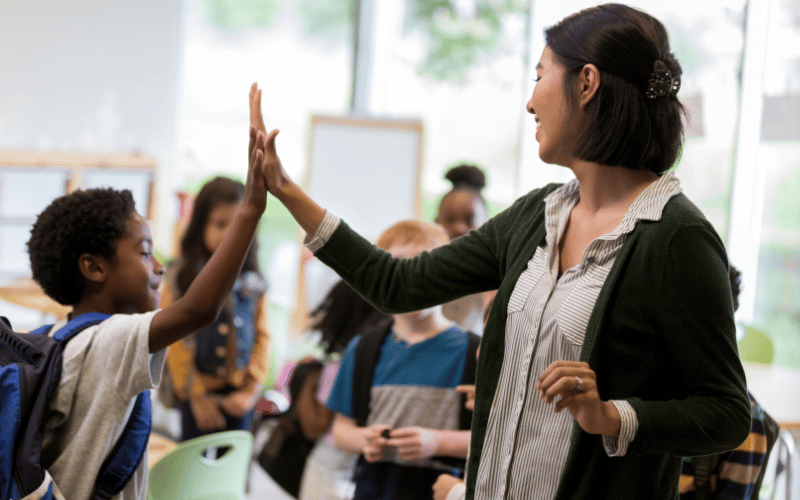 A teacher gives an high five to her student.