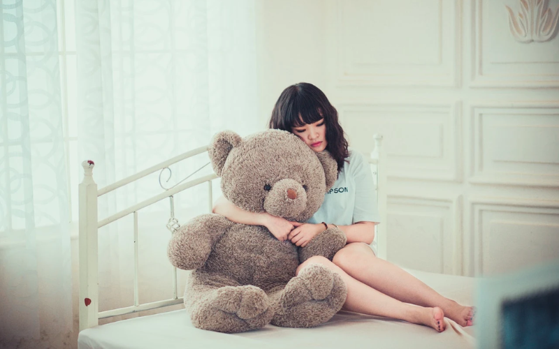 female holding a teddy bear on a bed