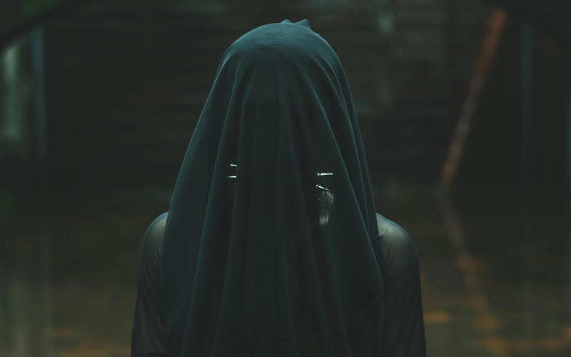 creepy figure with a black cloth covering face