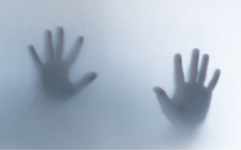 defocused scary ghost hands behind a white glass background