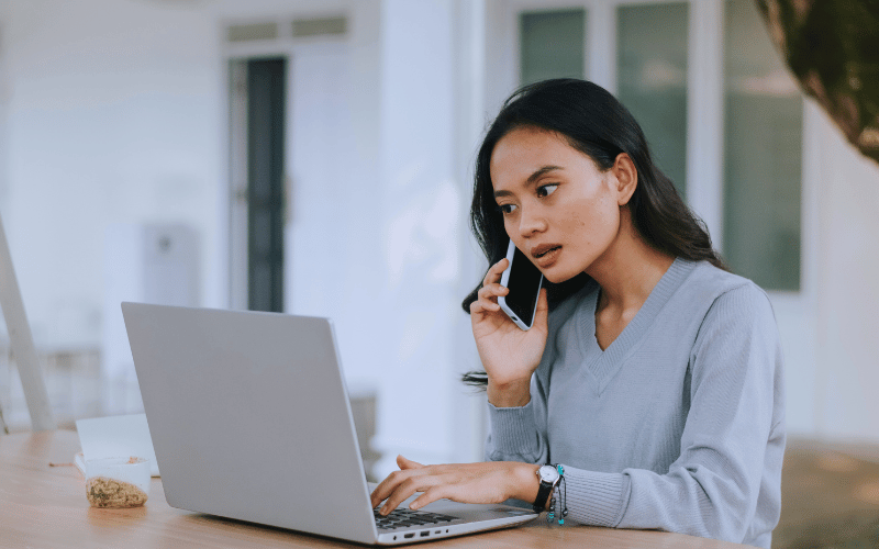 Woman using her laptop while on a phone call