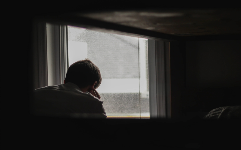  A person feeling depressed in front of the window of the room