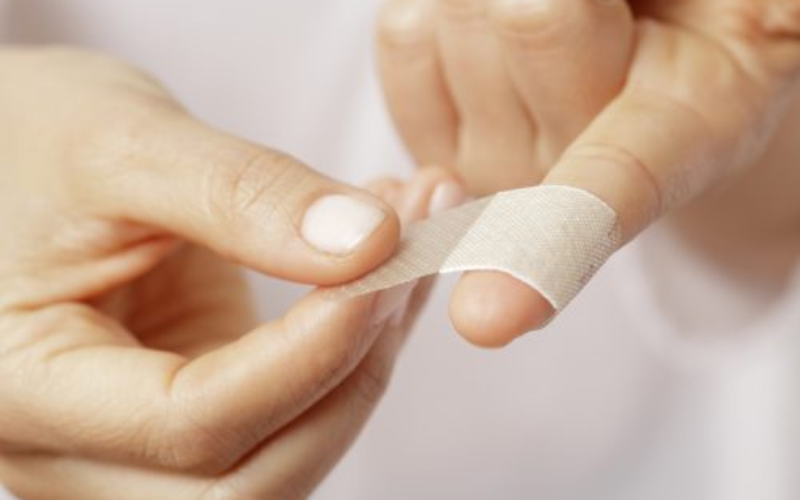 person tying band aid on finger