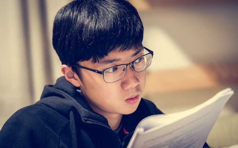male wearing hoodie looking at notes