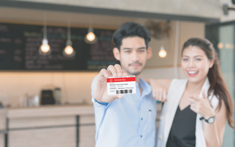 male showing student card and female pointing at student card