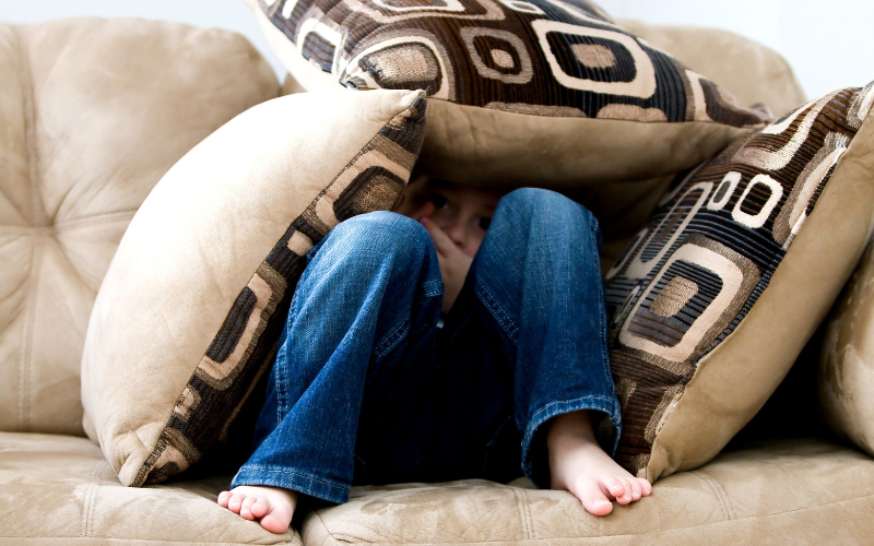 kid hiding in a few pillows