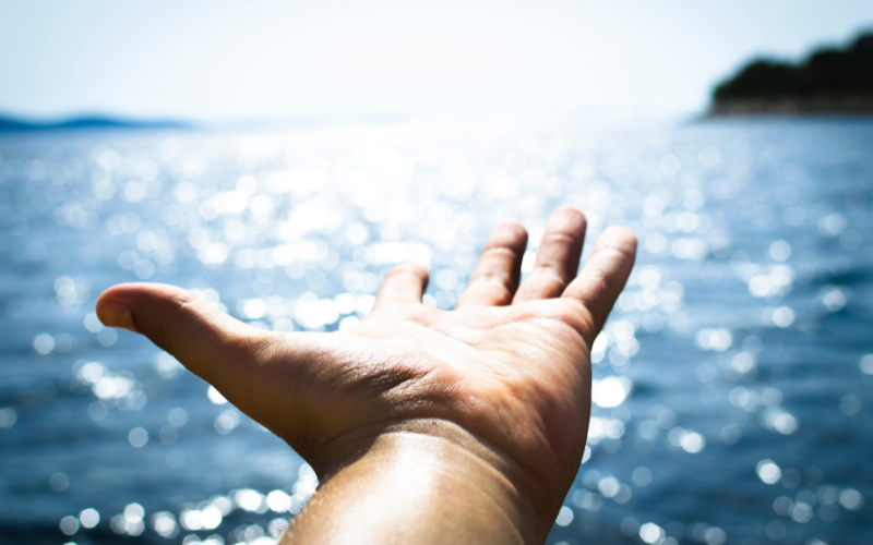 hand reaching out to the ocean