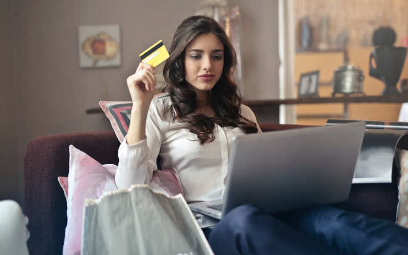 Lady looking at laptop with card in hand