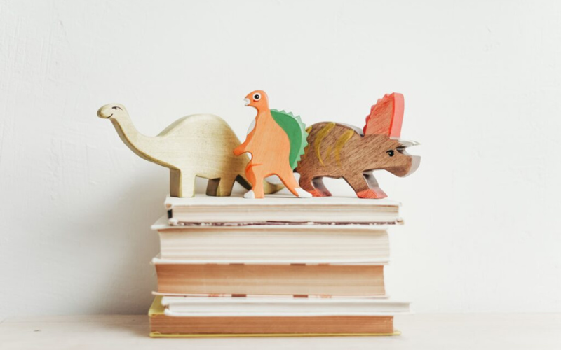Several dinosaur models on a stack of books