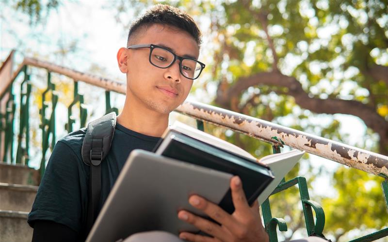 student sitting on stairs and reading a book