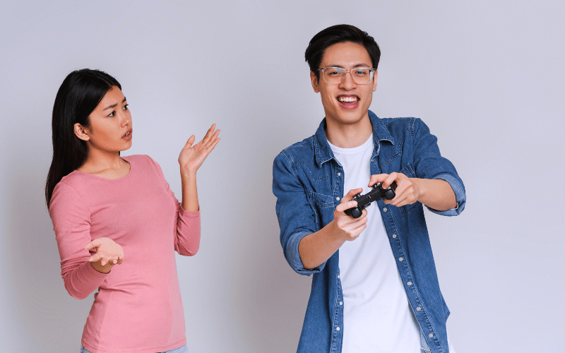 Man playing video games while woman looks at him in shock
