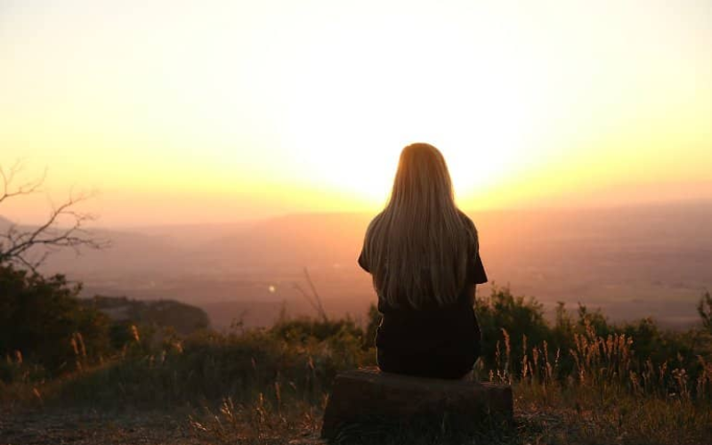 A girl is sitting on the top of the mountain