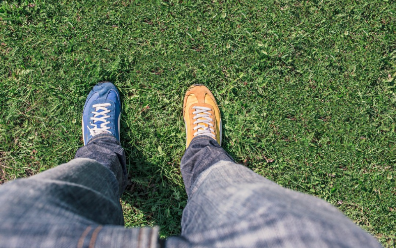 man wearing 2 different colour shoes on a grassy field
