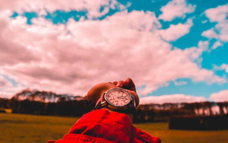 hand wearing a watch pointing towards the sky