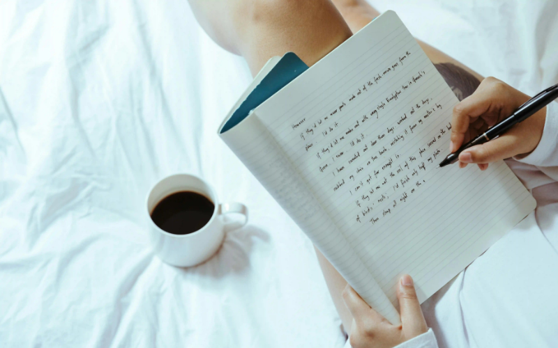 Writing in a notebook on a bed
