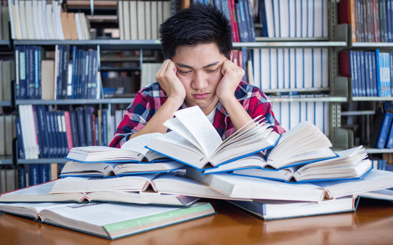 Man unhappily looking at a pile of books