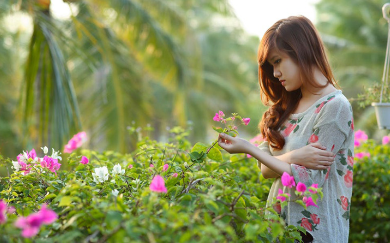 A girl looking longingly at the flowers in a garden