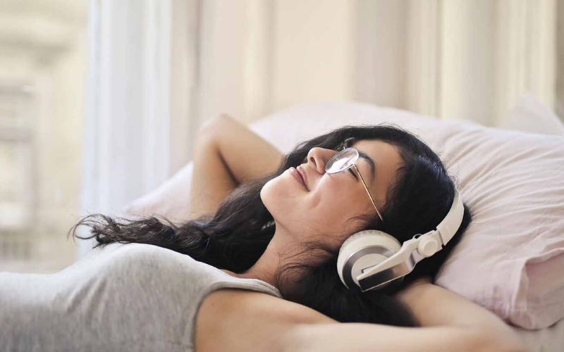 A girl lying on the bed listening to music