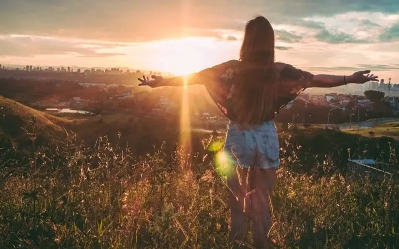 A Lady with arms stretched out facing sun