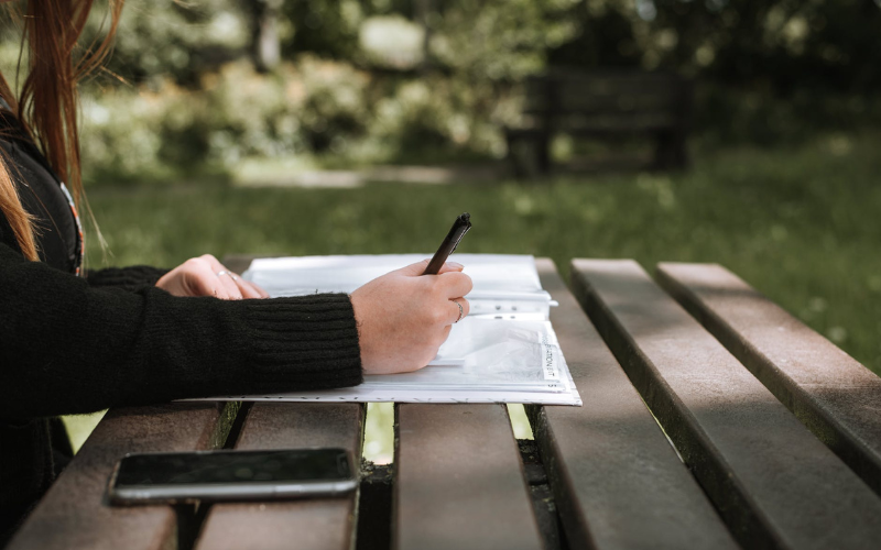 A lady writing something on a wooden table