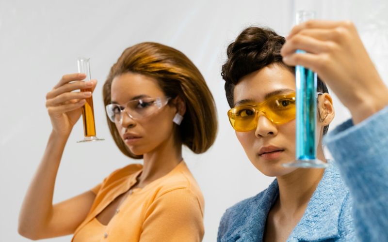 Two ladies holding measuring cylinders filled with liquid