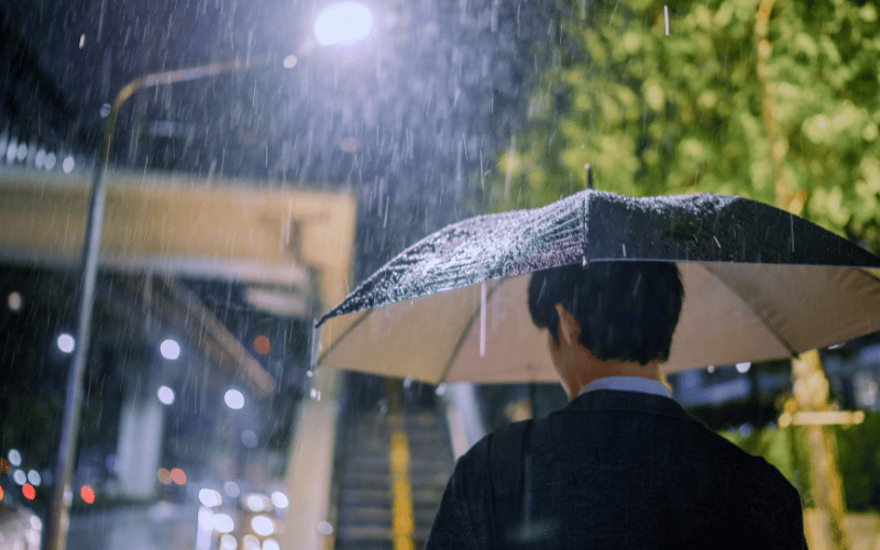A guy with his umbrella standing under the rain