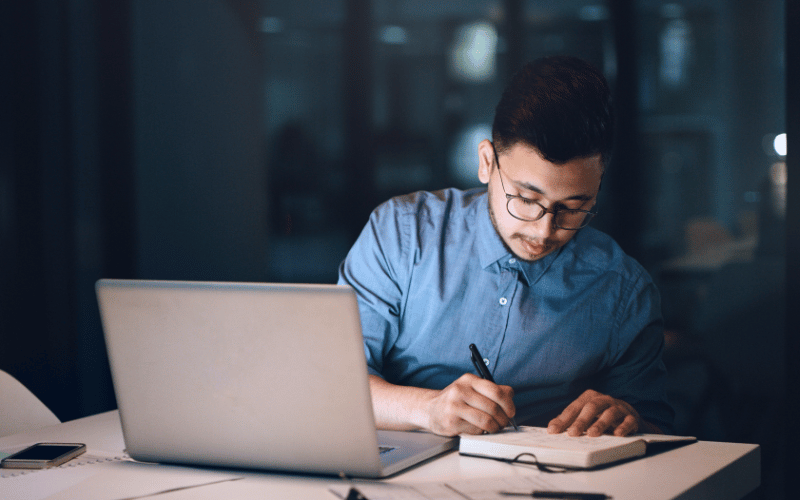 Guy writing notes in the office during night