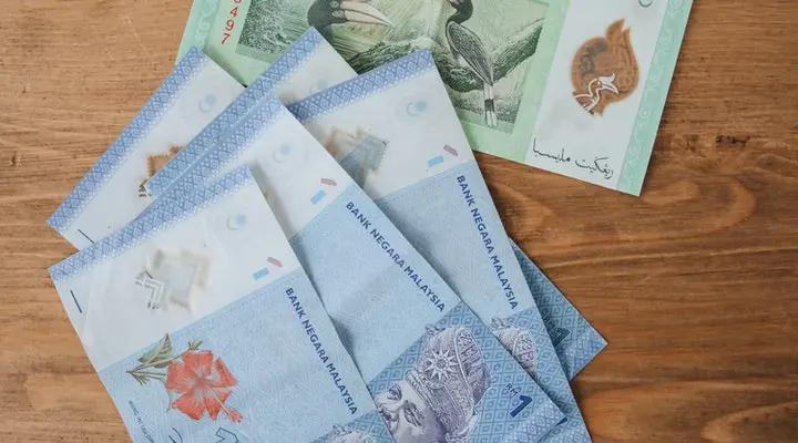 RM 1 and RM5 notes on the wooden surface