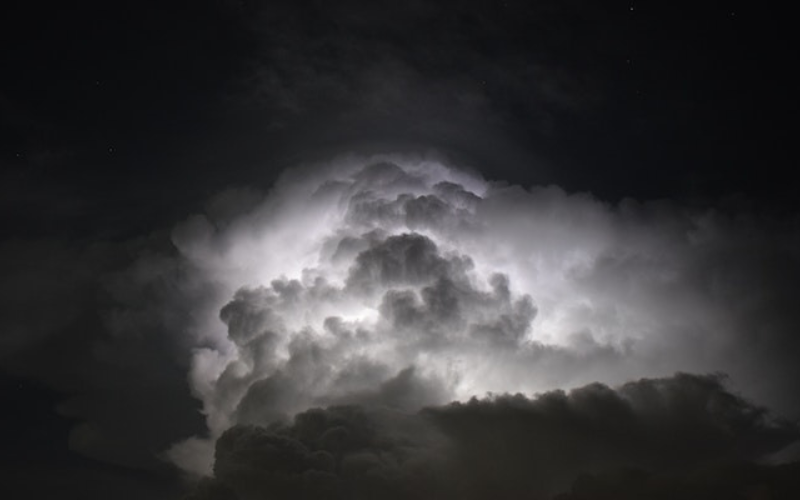 Bright light illuminates behind the dark clouds