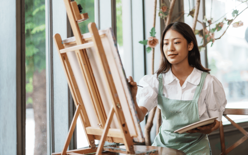 A woman paints on her canvas board