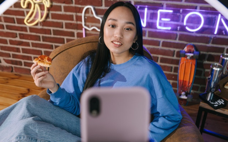 A girl eats a pizza and watch video on phone 