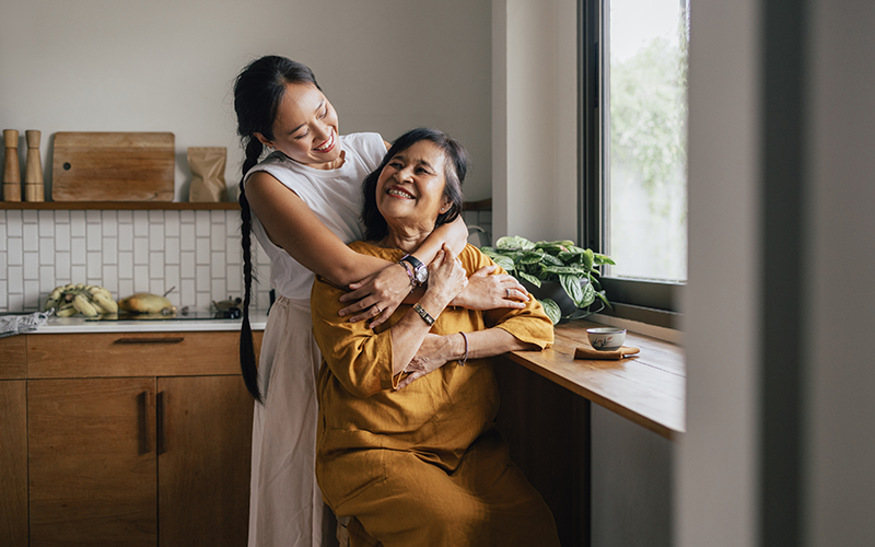 Adult woman hugging her mother in the kitchen