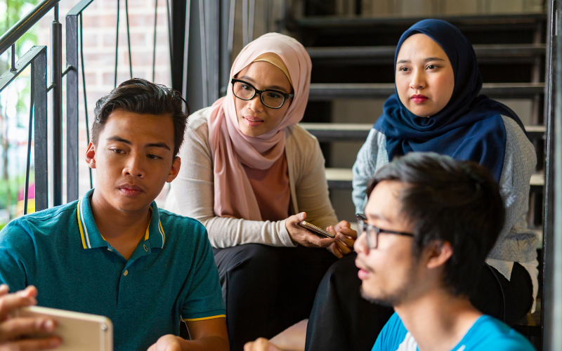 Malaysian youths watching a video on a smartphone