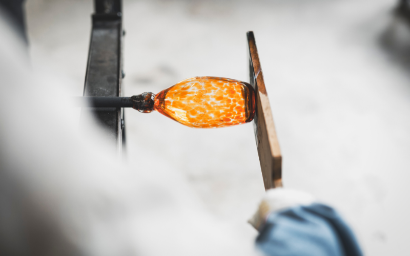 Glassblower flattens glass with a paddle
