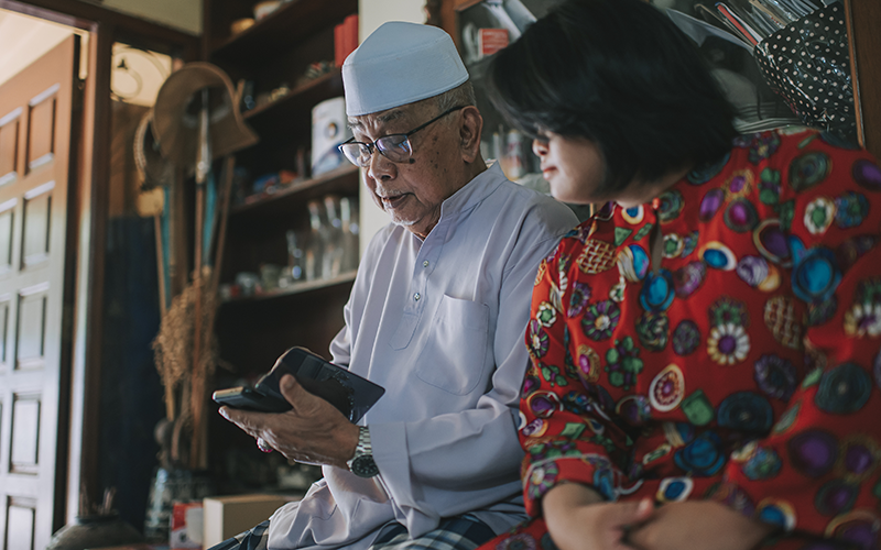 Grandfather using a smartphone while granddaughter looks on