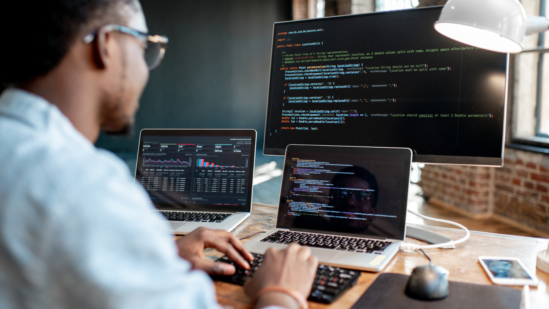 Man writing computer code across multiple screens