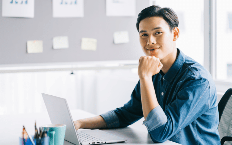Man smiling with laptop on the desk.