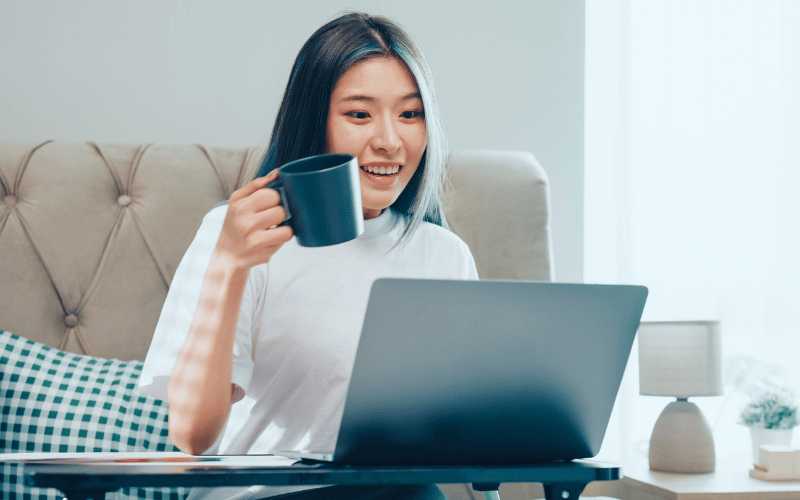  Lady holding a cup in front of her laptop