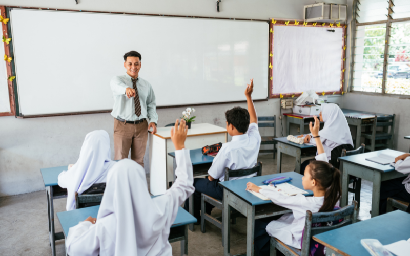 A male teacher teaching students in a classroom