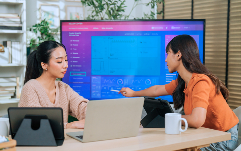 Two ladies analysing data on the TV screen 