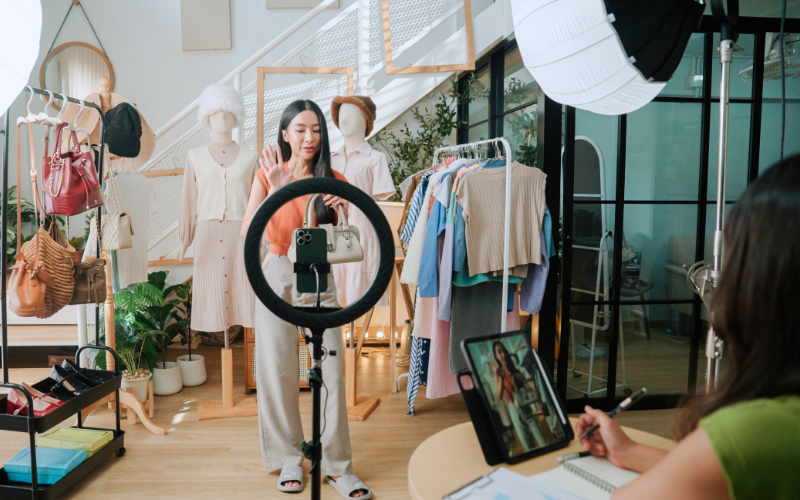 One lady is doing live streaming while her colleague is managing the paperwork