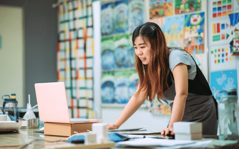 Asian woman looking at the laptop while standing