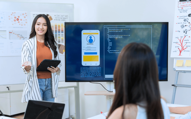 Lady presenting with a tv screen that shows user app prototyping 