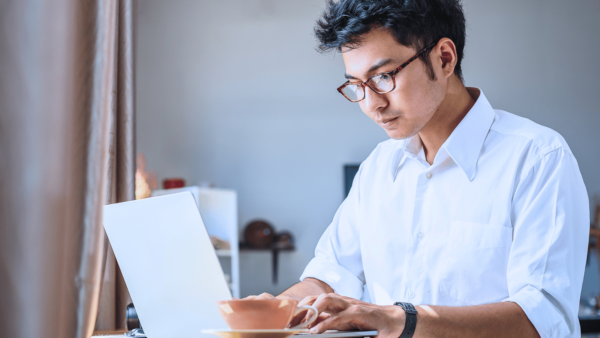 A man in specs is on his laptop